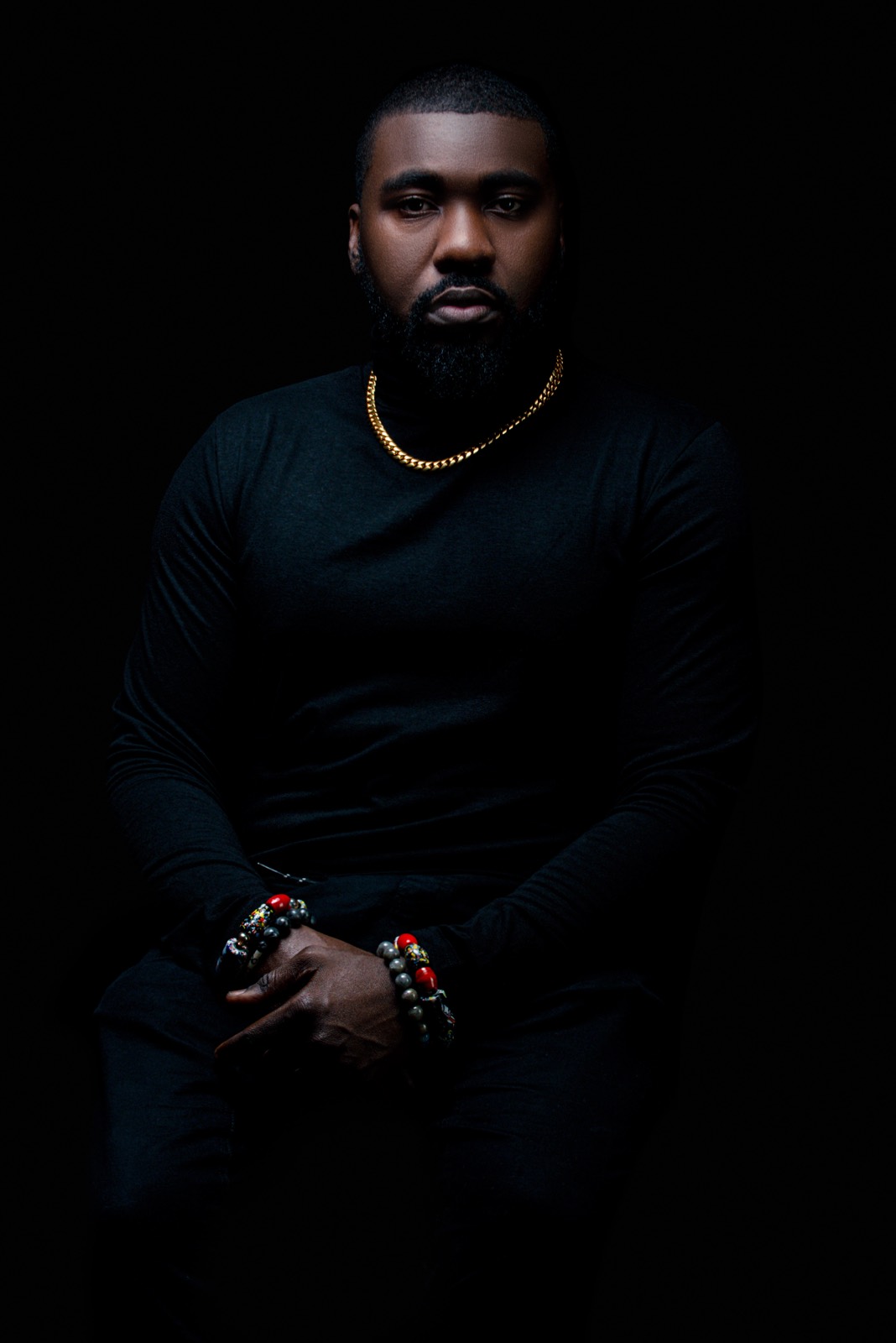 Studio portrait of DJ OMG PRINCE in black against a dark backdrop